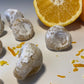 Pizzicotti Orange: Soft almond cookies along with an orange cut in half over a white background