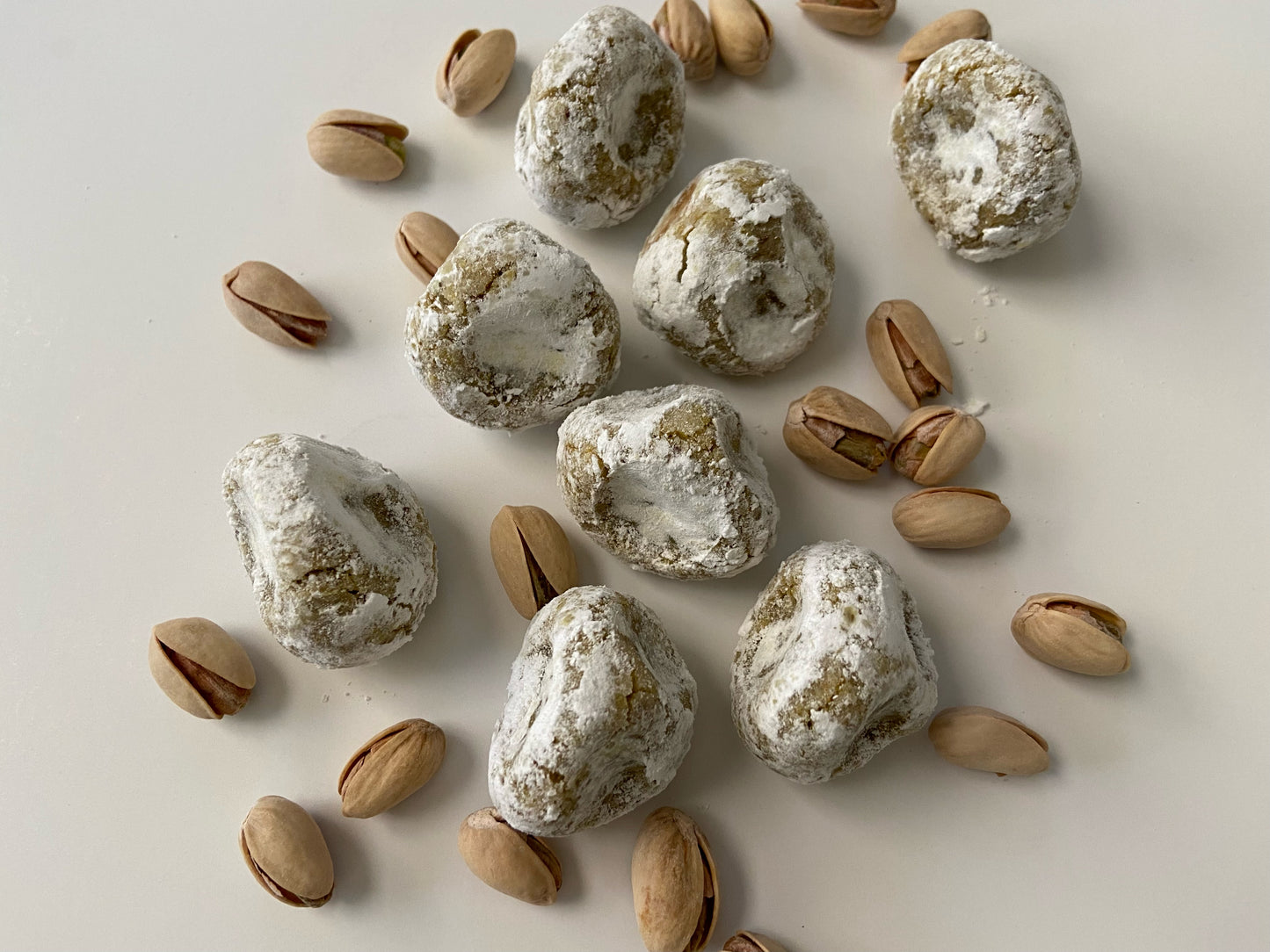 Italian style gluten free Soft almond cookies, pistachio flavor along with roasted pistachios over a white background