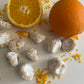 Pizzicotti Orange: Soft almond cookies along with an orange cut in half over a white background