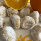 Pizzicotti Orange: Soft almond cookies along with an orange cut in half over a white background